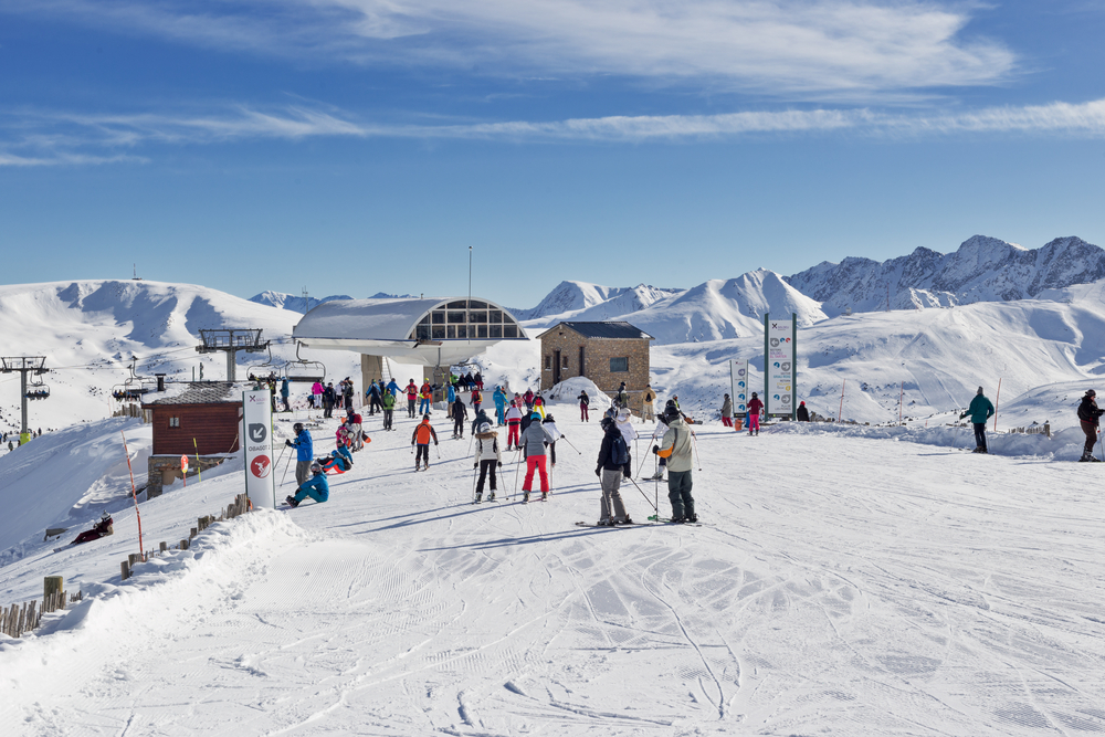 PYRENEES, ANDORRA - FEBRUARY 9, 2018: Unidentified tourists on skis got off the chairlift at the top of the mountain.  Sunny winter day, frost and sun