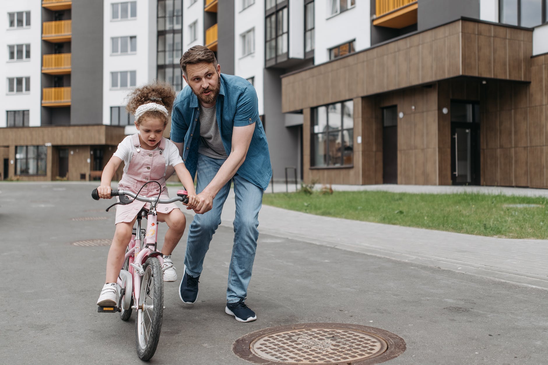 man teaching his daughter how to ride a bicycle