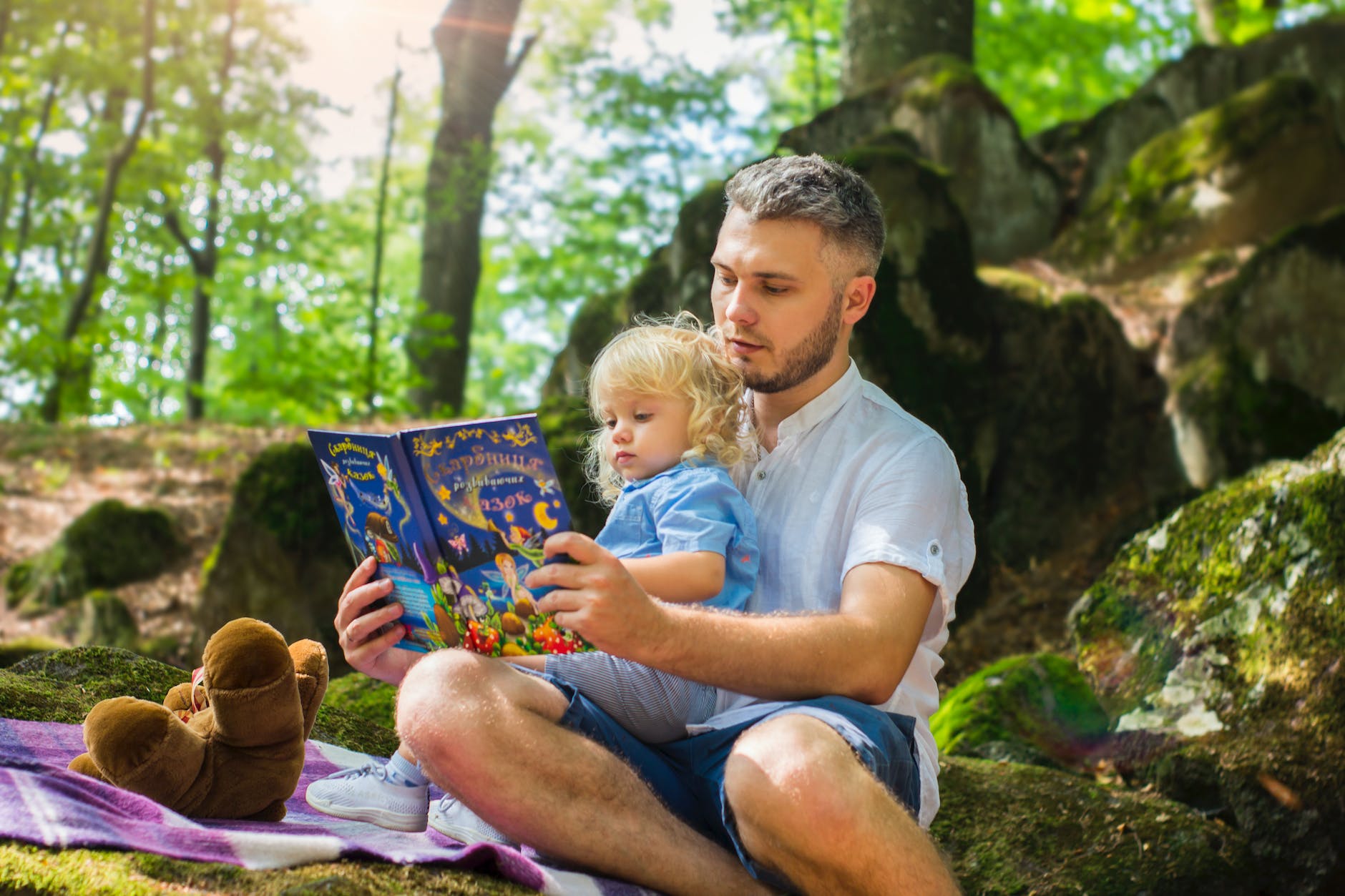 photo of man and child reading book during daytime