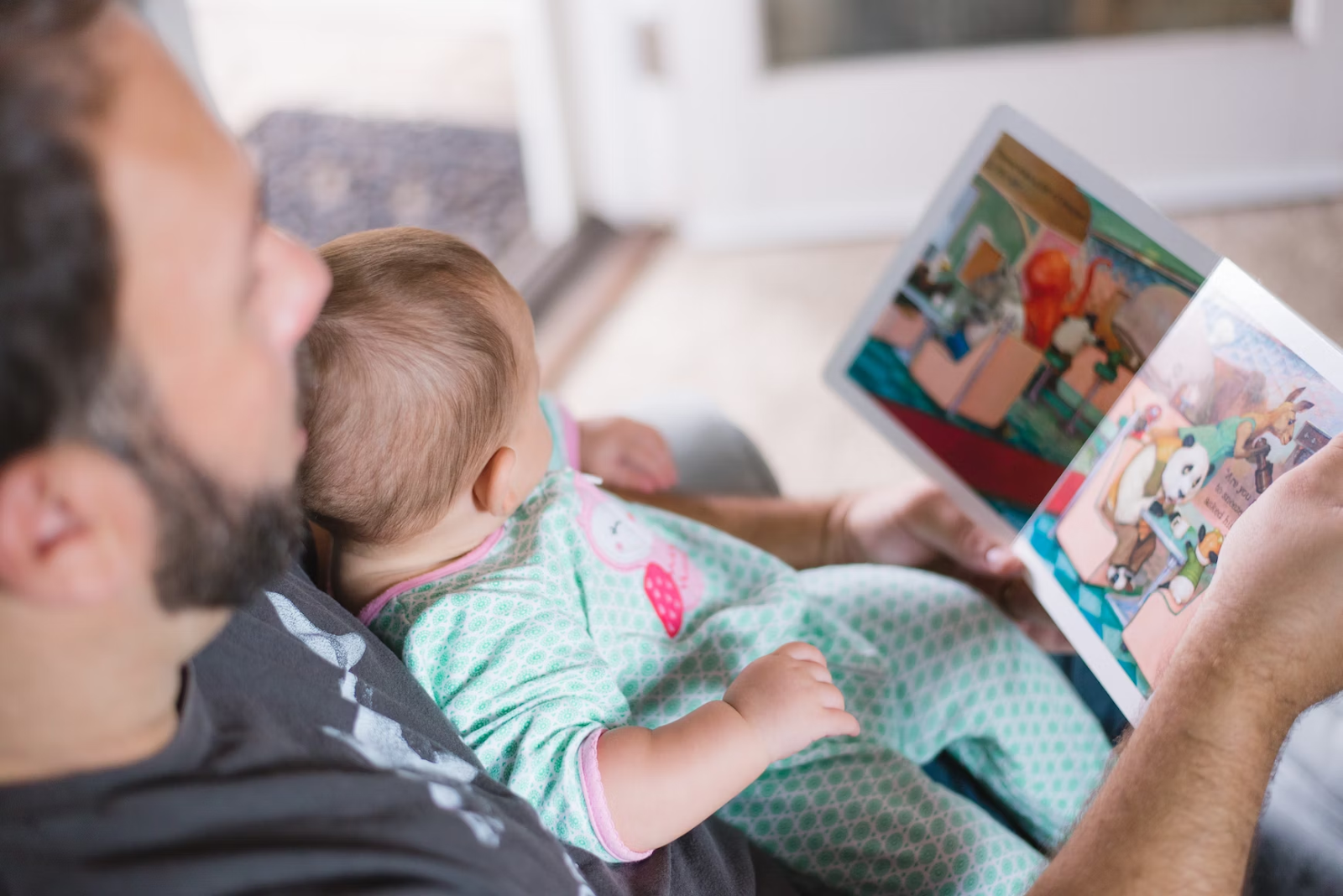 baby looking at book with dad