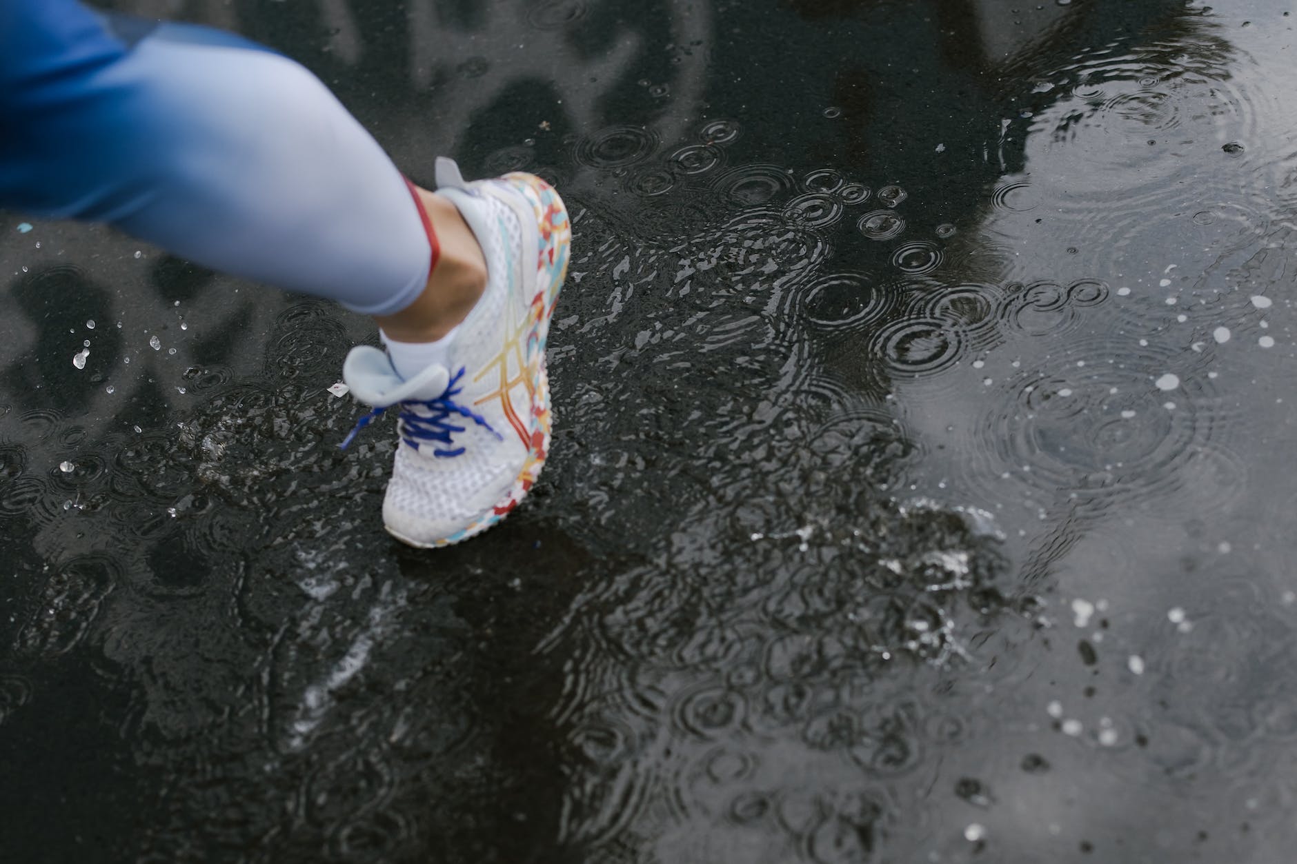 a person wearing a white shoes while stepping on wet road