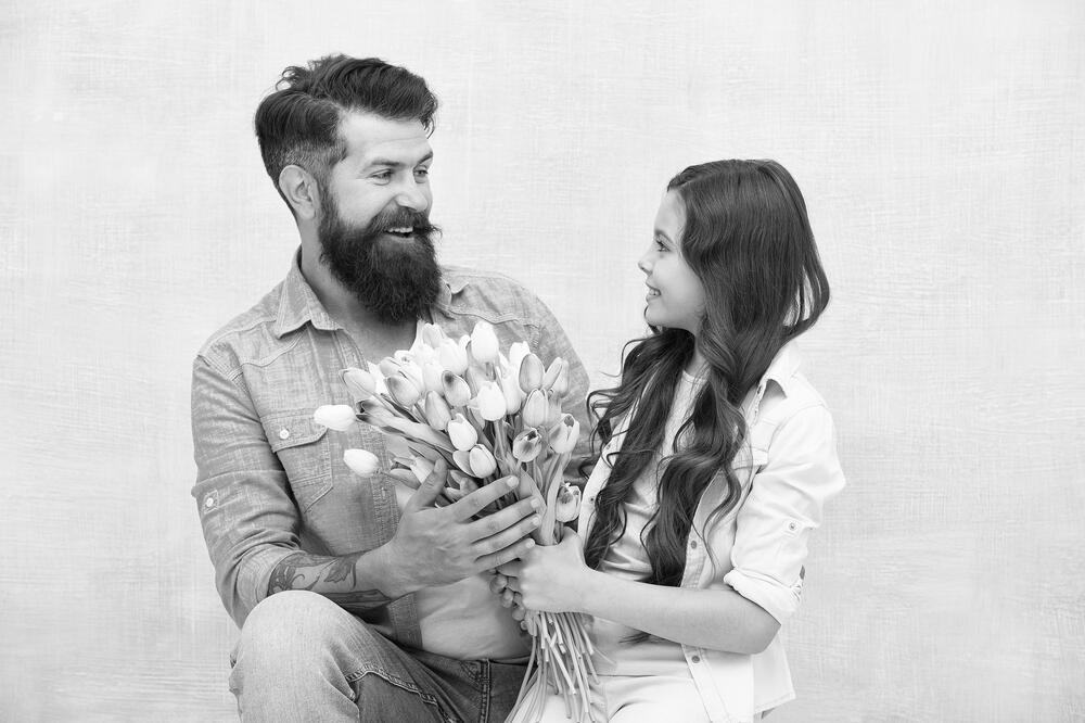 happy father got gift on fathers day. 8 March. International Women Day. dad congratulate small girl on holiday and give flowers. family day. spending time together. daughter take tulip flower bouquet.
