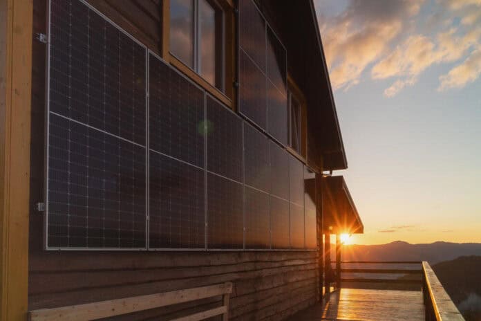 Solar panels on a wooden cabin wall. Beautiful, large modern house and solar energy.