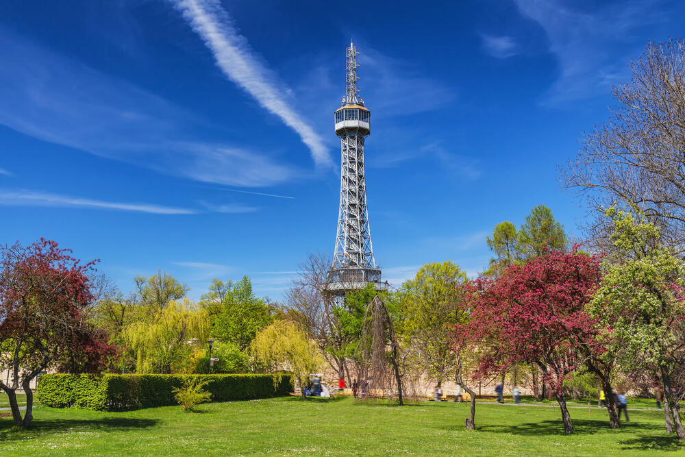 Petrin Lookout Tower in Prague surrounded by blossoming trees and greenery, a popular scenic viewpoint often called Prague’s Eiffel Tower.