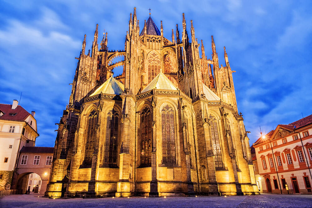 Illuminated St. Vitus Cathedral in Prague at dusk, showcasing its Gothic architecture and intricate stained glass windows, a top historic attraction in the Czech Republic.
