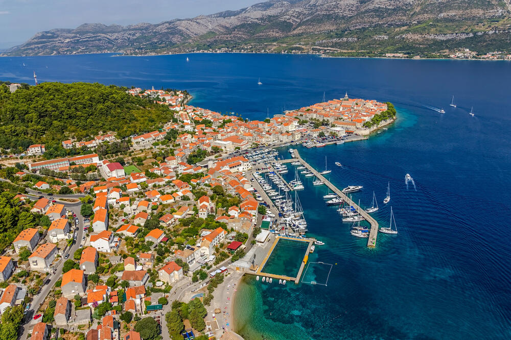 Aerial view of Korčula Old Town, Croatia, with its medieval architecture, scenic marina, and clear Adriatic waters—ideal for a family island-hopping adventure.