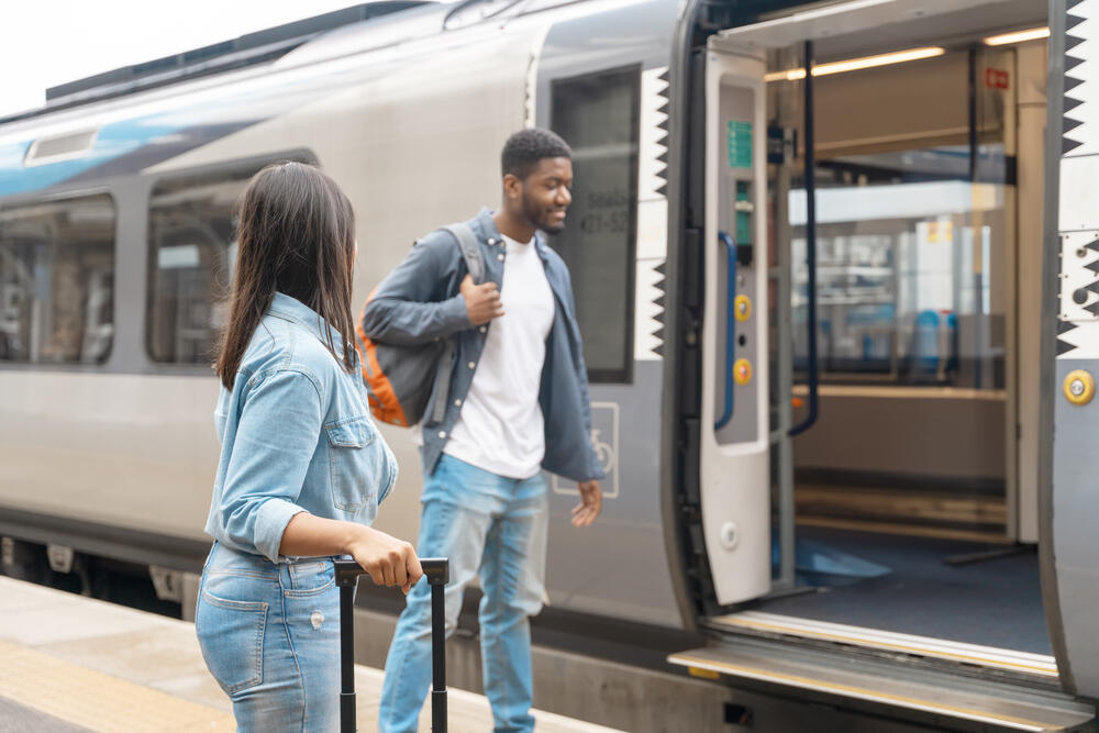 Young couple boarding a train together to save on transport costs with railcards and budget travel options