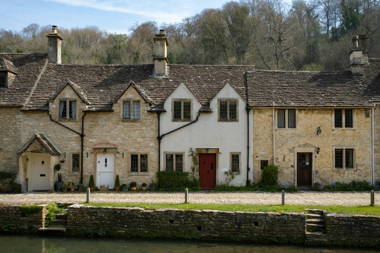 Charming row of traditional stone cottages by a riverside in a picturesque English village, perfect for countryside Airbnb or holiday rental stays