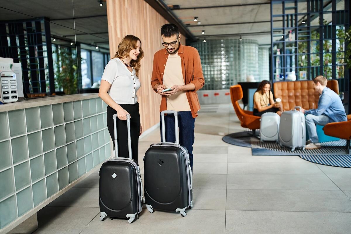 A couple with suitcases checking travel information on a smartphone in a modern hotel lobby, highlighting the importance of digital access while travelling.