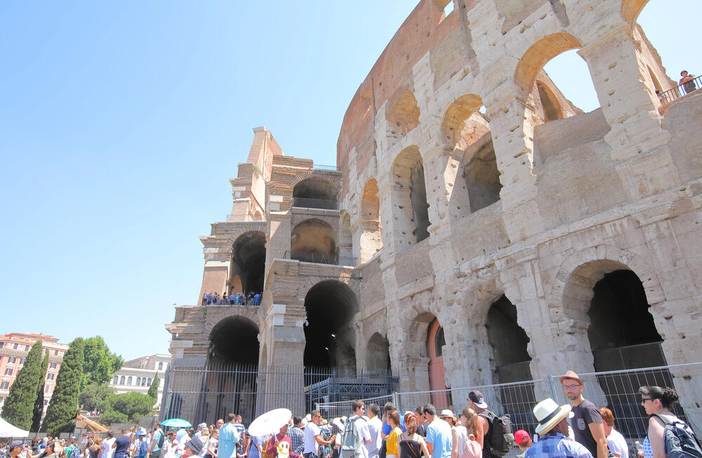 Tourists visiting the Colosseum in Rome, Italy on a sunny day, exploring the ancient Roman amphitheatre, one of the top attractions for first-time visitors to Italy.